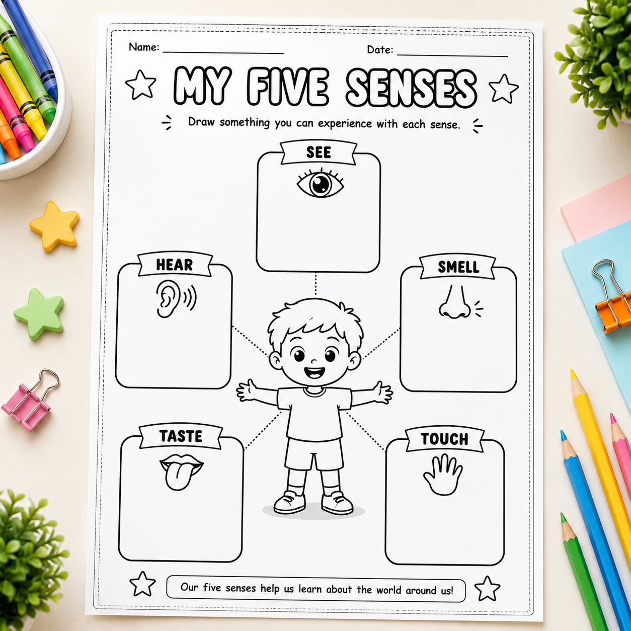 A children's educational worksheet titled 'MY FIVE SENSES' laid flat on a light beige desk. The black-and-white printable sheet shows labeled boxes for See, Hear, Smell, Taste, and Touch around a cartoon child, with writing spaces at the top and bottom.
